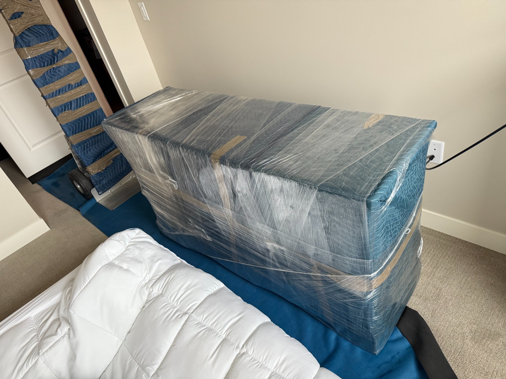 Mattress and furniture fully wrapped in stretch film and moving pads
